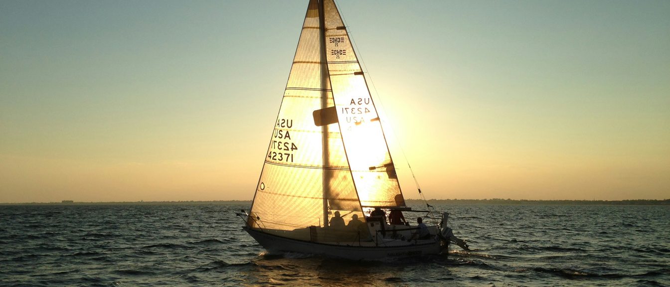 Calm water at dusk with a distant sail